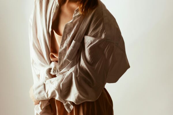 Trendy woman posing in oversized shirt and sunglasses, exuding modern fashion style.