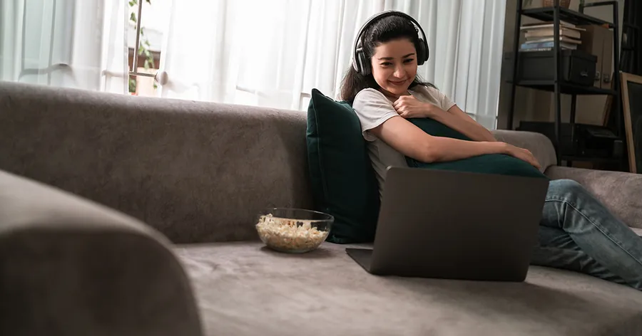 Person relaxing on a couch watching a movie on a laptop