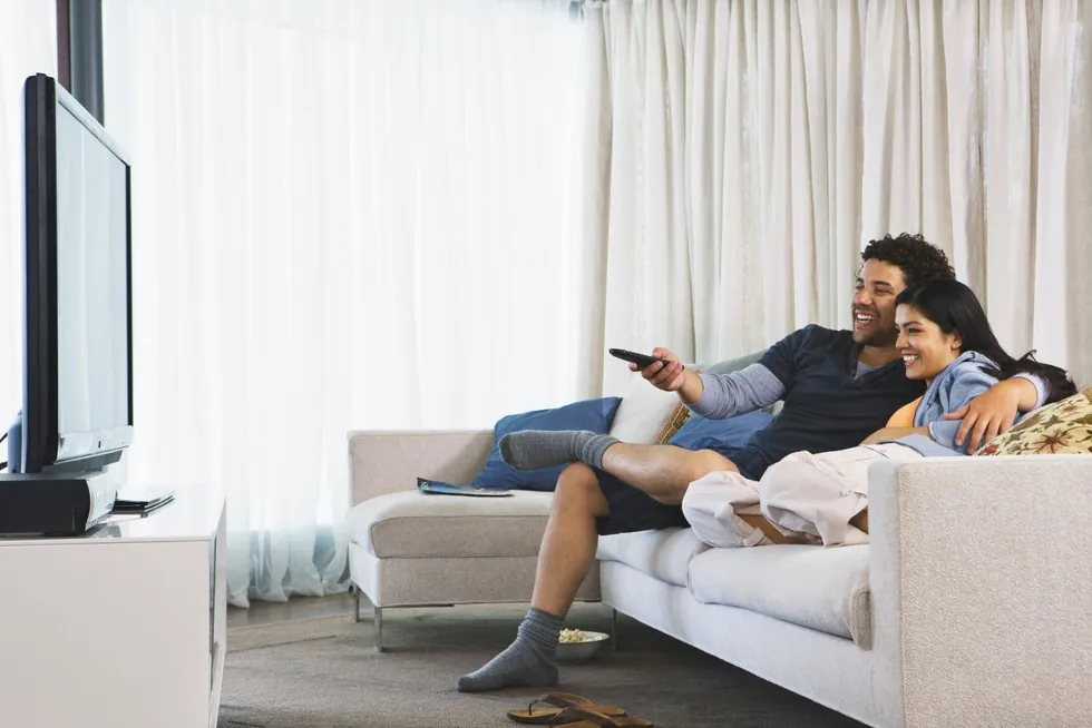 Couple watching TV together in their living room in the evening